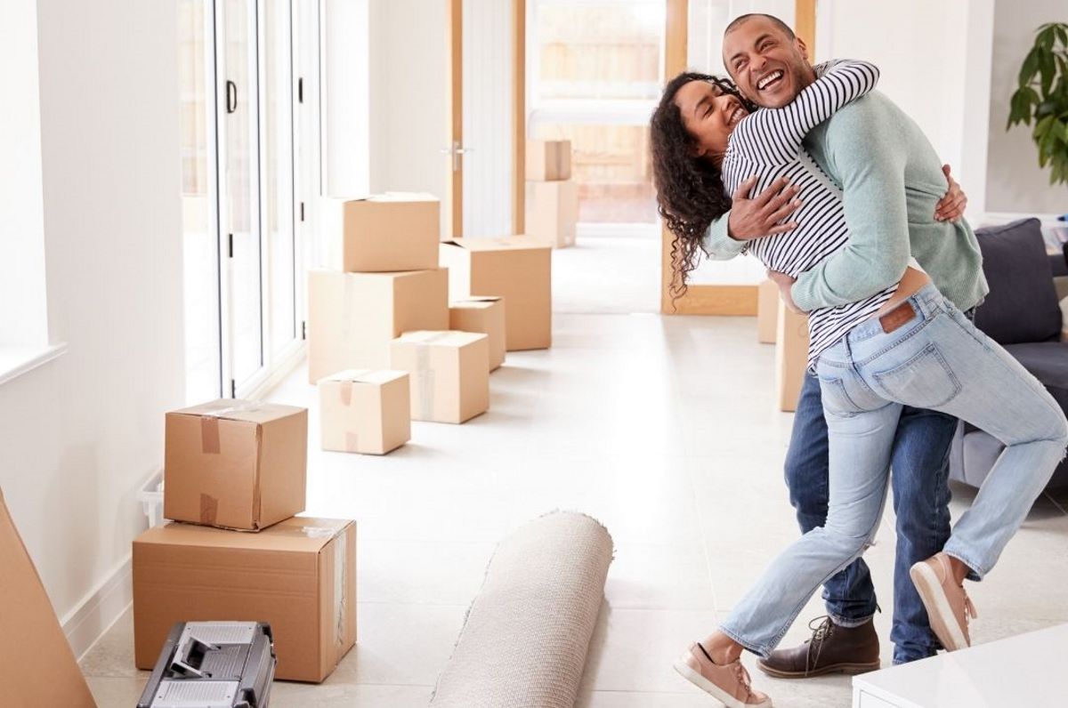 Couple huggin with moving boxes